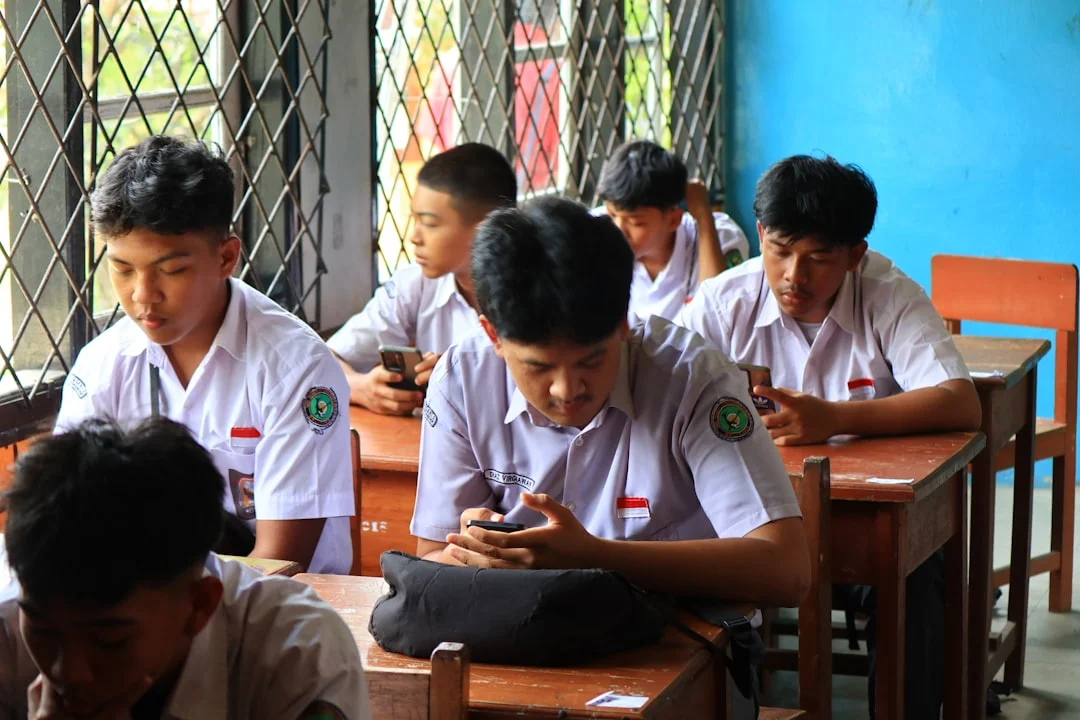 Stuents in uniform using phones in classroom. (Fot. Fajar Herlambang STUDIO / Unsplash)