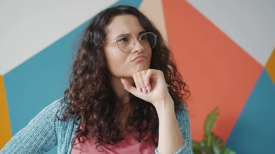 Woman with glasses thinking with hand on chin (Fot. Vitaly Gariev / Unsplash)