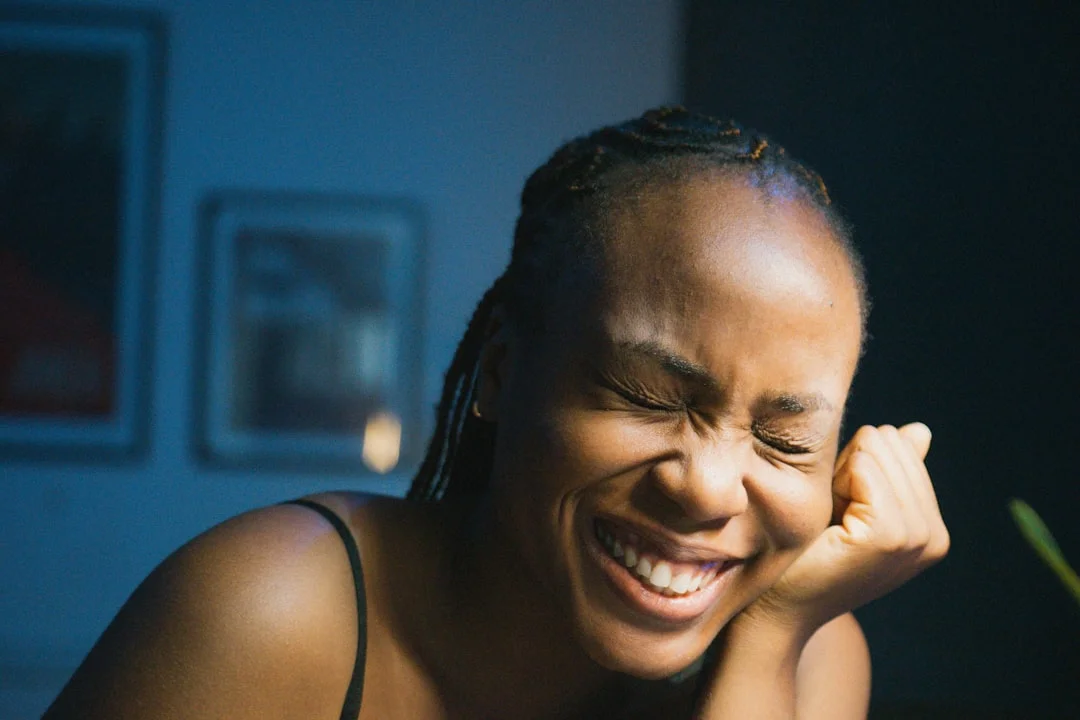 a woman laughing while sitting at a table (Fot. Stephen Okonkwo / Unsplash)