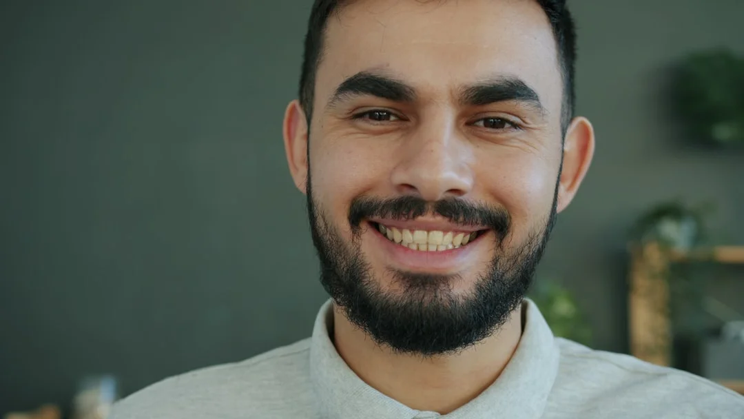 A smiling man with a beard wearing a collared shirt. (Fot. Vitaly Gariev / Unsplash)