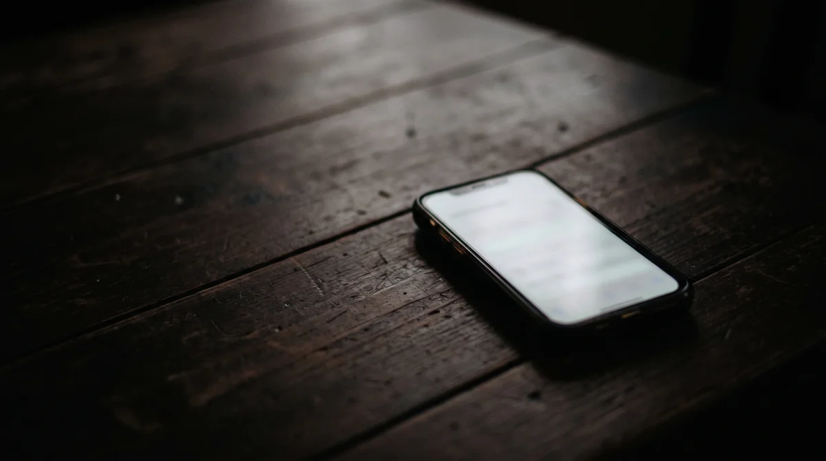 Smartfon świecący w ciemności na drewnianym blacie, symbol sięgania po pomoc w kryzysie